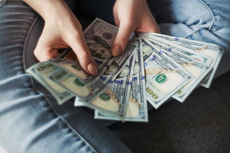 یک دسته صد دلاری در دستان یک شخص